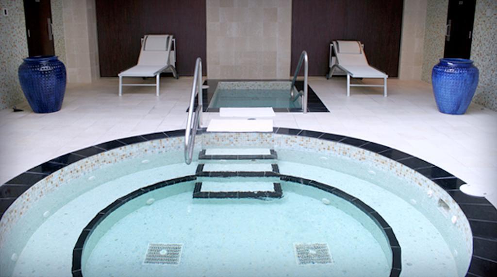 Hard Rock Hotel & Casino Biloxi Exterior foto The photo shows a spa area featuring a circular hot tub or jacuzzi, surrounded by a black stone border. There are steps leading into the water, and the interior of the tub appears to be tiled. In the background, there are two white lounge chairs posi