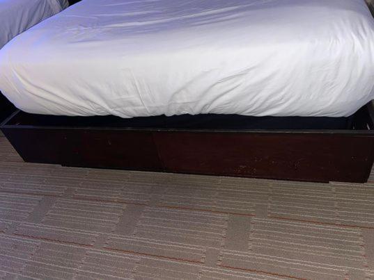Hard Rock Hotel & Casino Biloxi Exterior foto The photo shows a bed with a white mattress and bedsheet. The bed frame is dark-colored wood, and there is a storage compartment or drawer visible underneath the bed. The flooring appears to be a patterned carpet. The overall setting seems to be a be