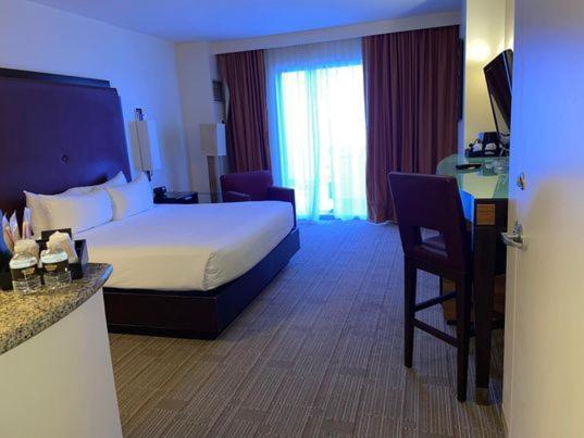 Hard Rock Hotel & Casino Biloxi Exterior foto The photo shows a hotel room with a modern and clean design. The room features a large bed with white linens, a nightstand, and a headboard. There is a window with sheer curtains that lets in natural light and provides a view of the outside. The floo
